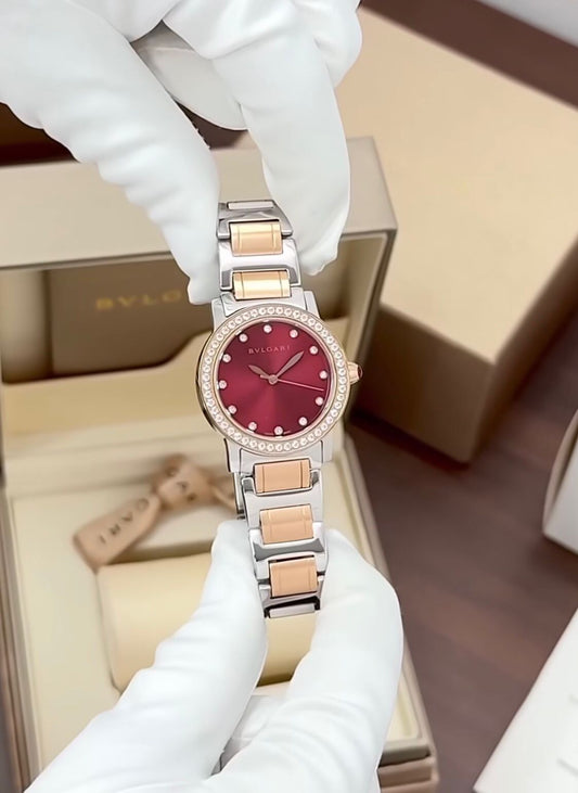 Bvlgari watch with a stainless steel and rose gold case, diamond bezel, and a red dial.