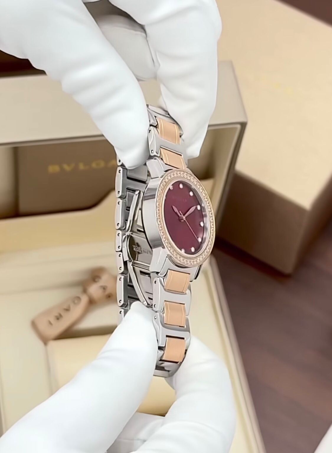 Bvlgari  watch with a stainless steel and rose gold case, diamond bezel, and a red dial.