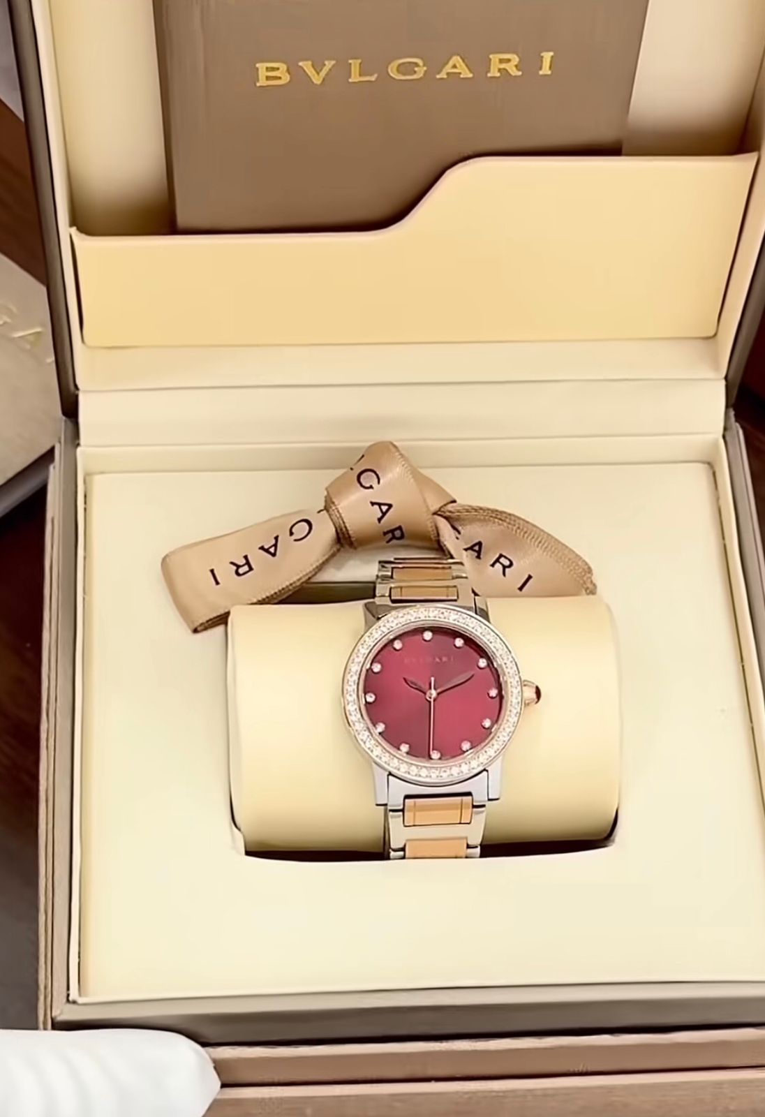 Bvlgari  watch with a stainless steel and rose gold case, diamond bezel, and a red dial.
